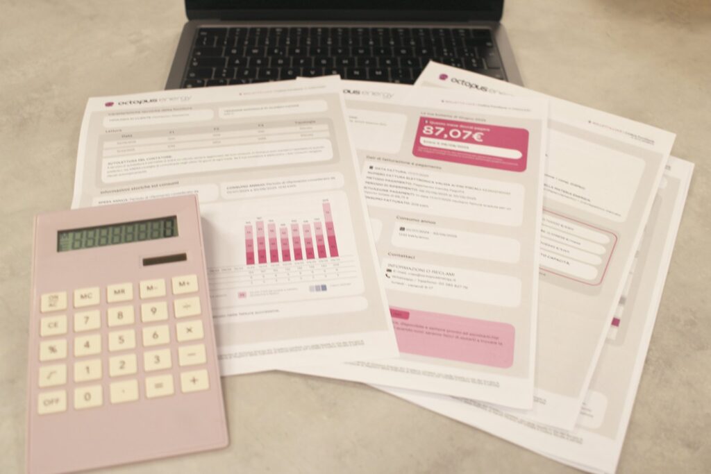 Facturas, calculadora y una computadora portátil sobre un escritorio