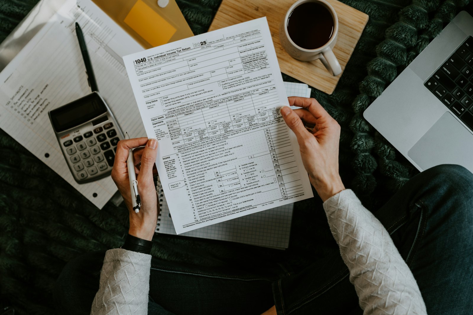 Manos sujetando formularios fiscales junto a una calculadora