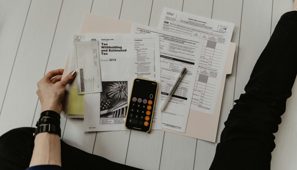 Persona revisando papeles con una calculadora y una pluma