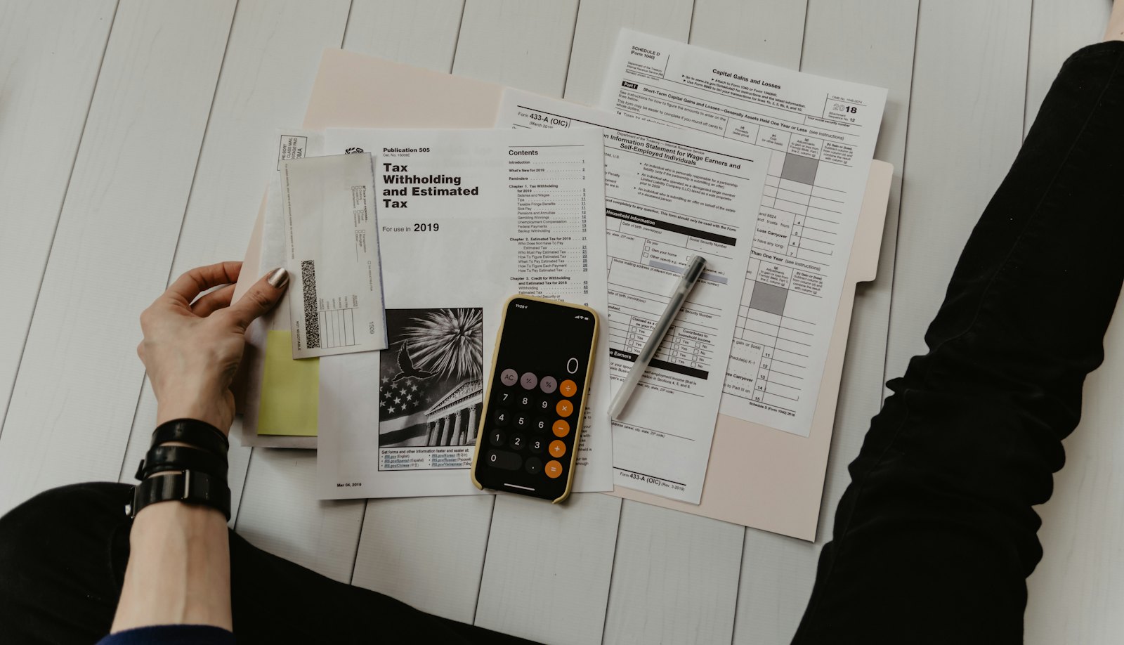 Persona revisando papeles con una calculadora y una pluma